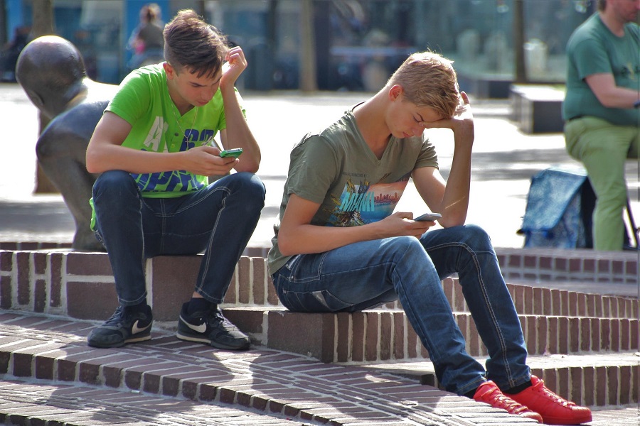 Pokemon Go Safety Tips Two Boys Sitting Outside Looking at Their Phones