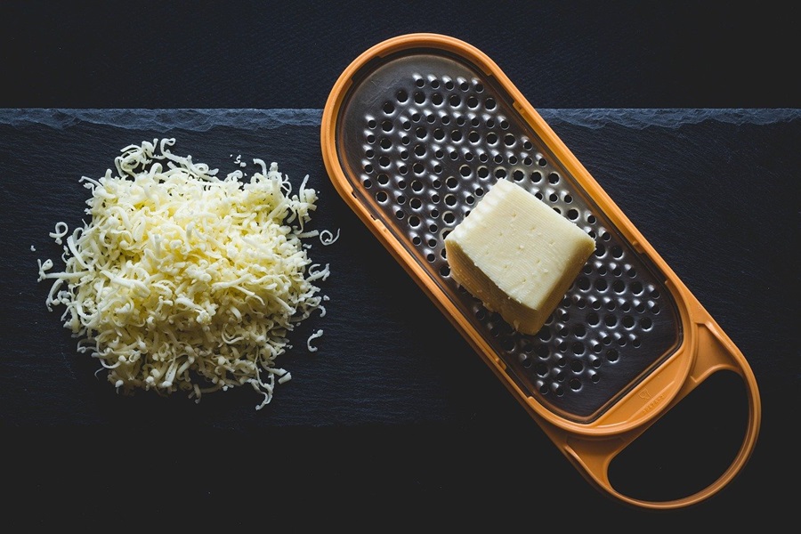Best Man Snacks to Keep on Hand Cheese on a Cheese Grater Next to a Pile of Shredded Cheese