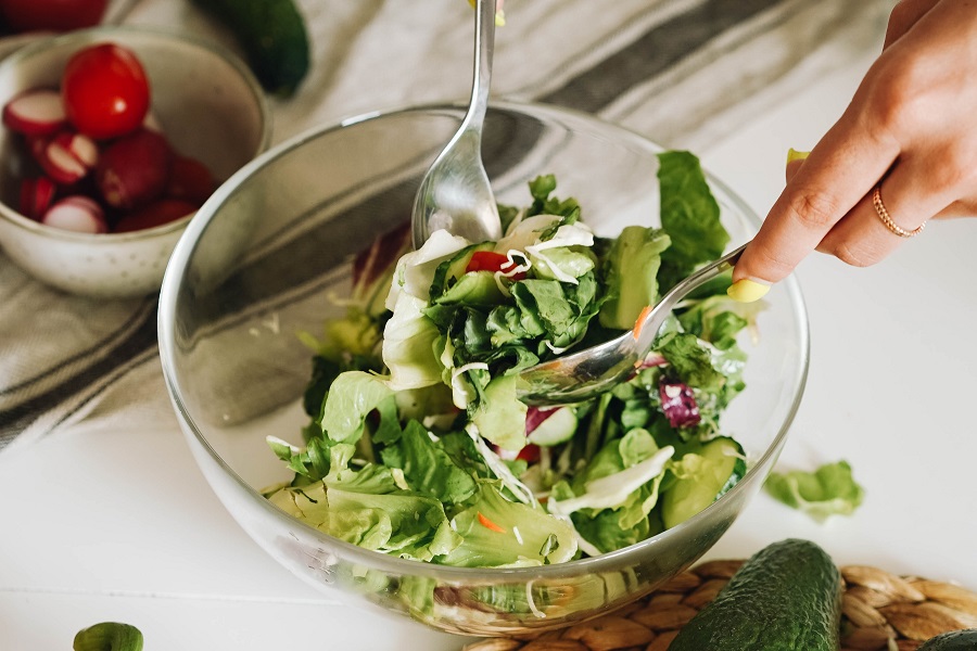 Whole30 Lunch Recipes Close Up of Someone Mixing Salad Together in a Glass Bowl