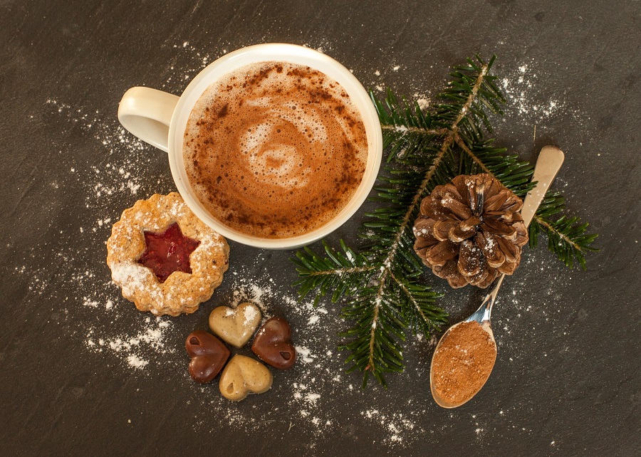Holiday Cookie Recipes Overhead View of a Cup of Hot Chocolate with Cookies, Pine Needles, and Pinecones Around it