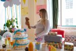 Baby Boy Gift Ideas a Pregnant Woman at a Baby Shower Holding Up and Looking at a Small Teddy Bear