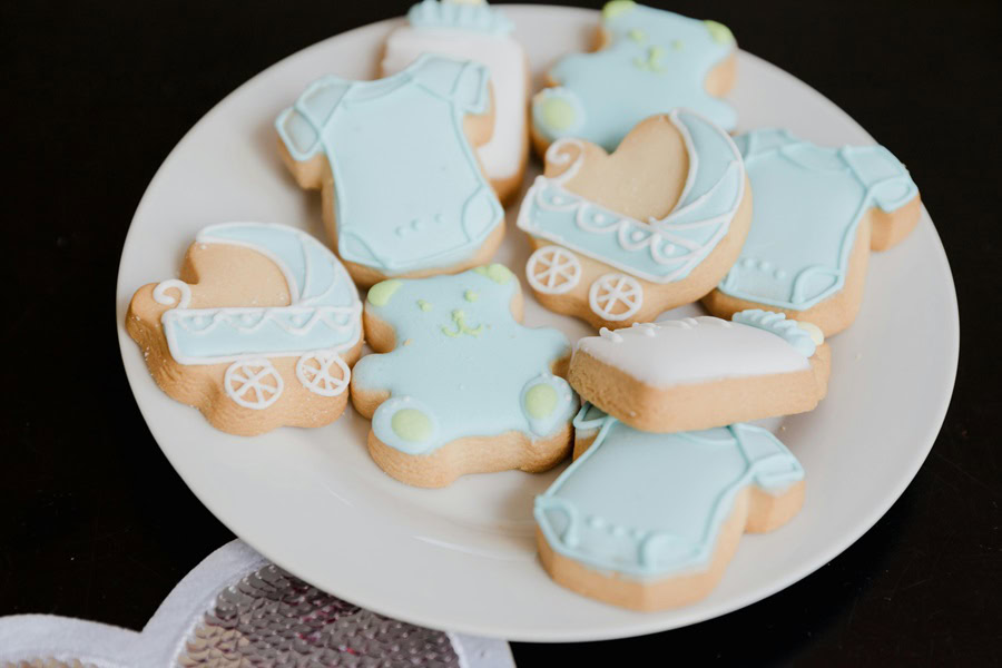 Baby Boy Gift Ideas Close Up of a Plate of Cookies Shaped Like Strollers and Bears with Blue Icing
