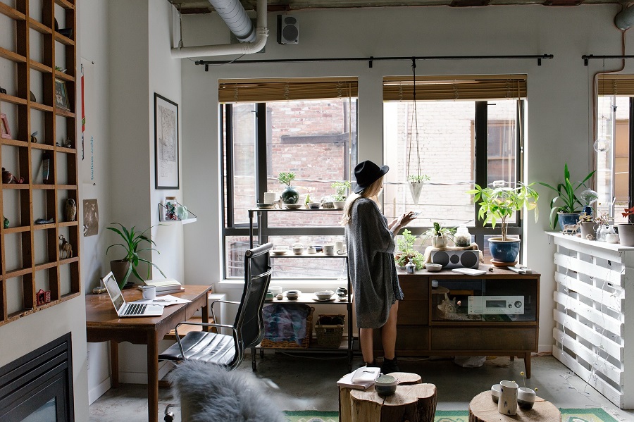 Office Decor Ideas for your Home Office A Woman Standing in a Studio Apartment with Plants and an Office Desk in One Corner