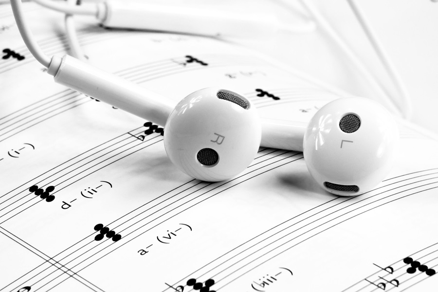 10 Songs to Listen to When you Want to Make a Deal Close Up of Earbuds on Sheet Music