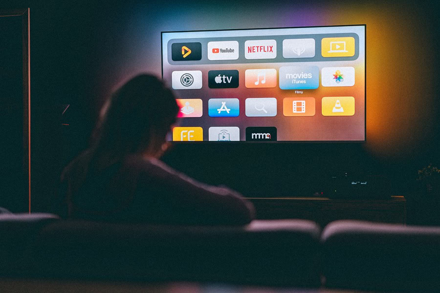 Netflix Shows to Watch After a Long Day at Work a Person Sitting on a Couch Looking at a TV in a Dark Room