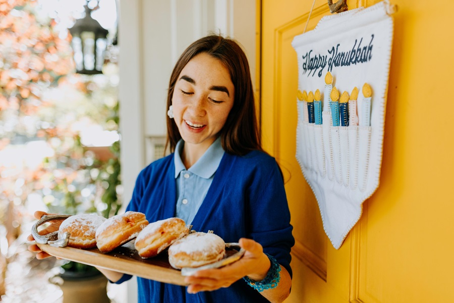 Mensch on a Bench Rules a Woman Bringing Sufganiyot to a Hanukkah Celebration