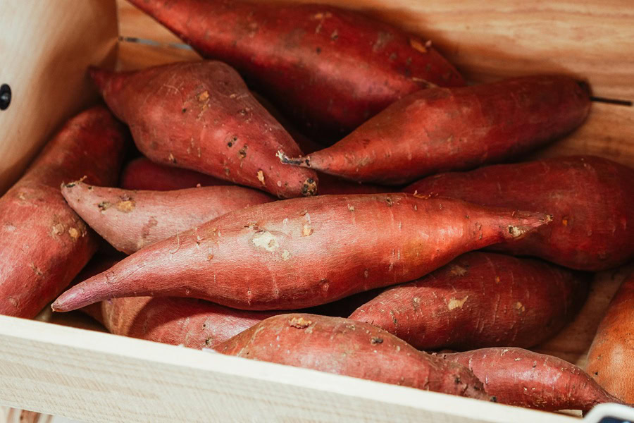 Clean Eating Breakfast Recipes Close Up of a Wooden Crate Filled with Sweet Potatoes