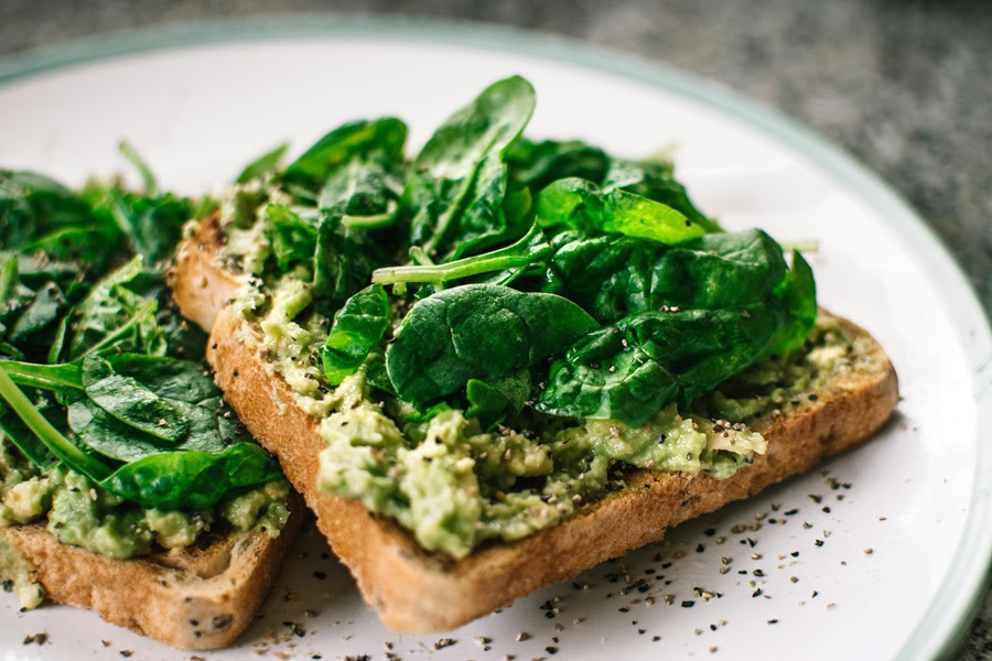 Clean Eating Breakfast Recipes Avocado Toast with Spinach on a Small White Plate