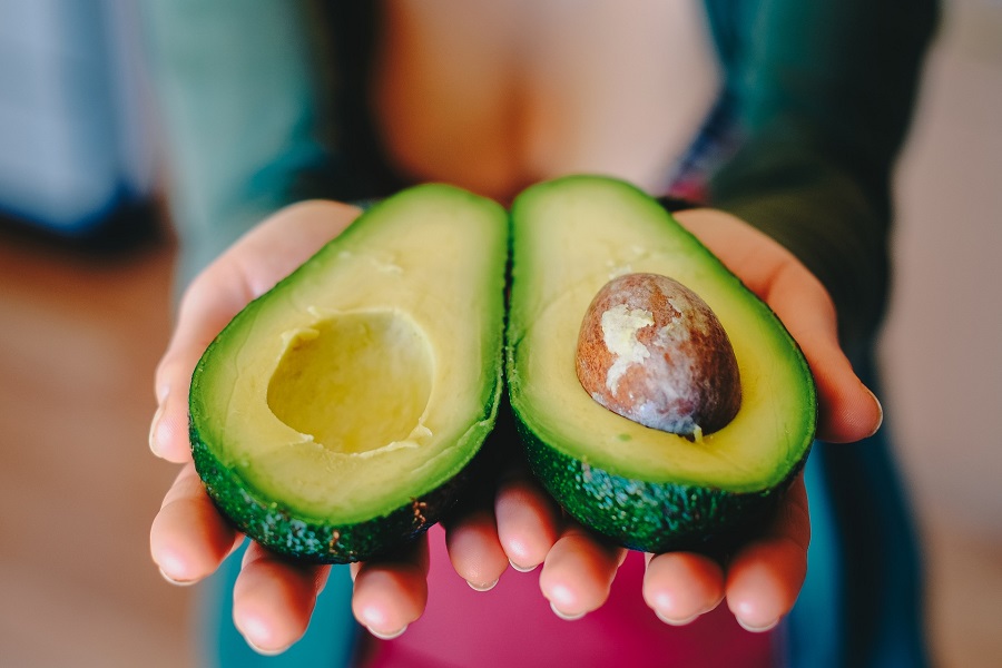Whole30 Diet Rules Woman Holding an Avocado That has Been Cut in Half