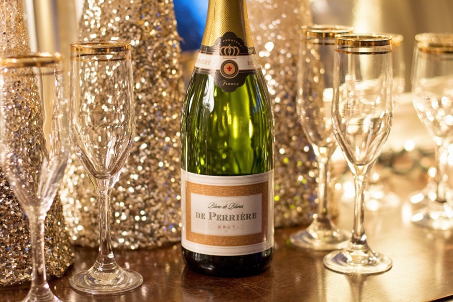 New Year's Eve Toast Quotes Close Up of a Bottle of Brut Next to Champagne Glasses and Sparkly Decor in the Background