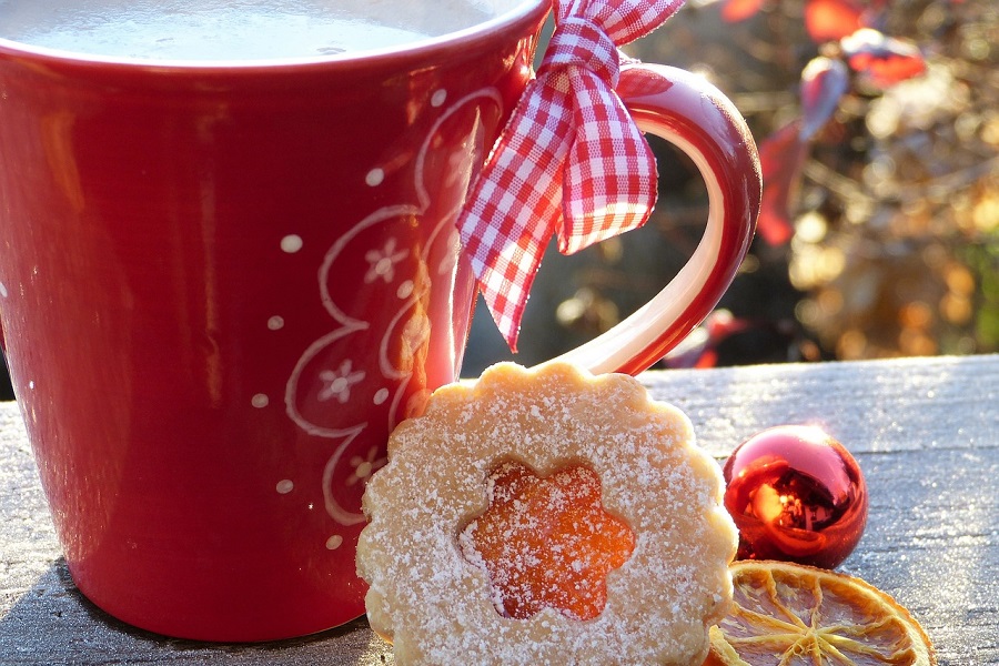 Things to Do on Christmas Morning Close Up of a Red Coffee Mug and a Shortbread Cookie with Christmas Decor in the Background