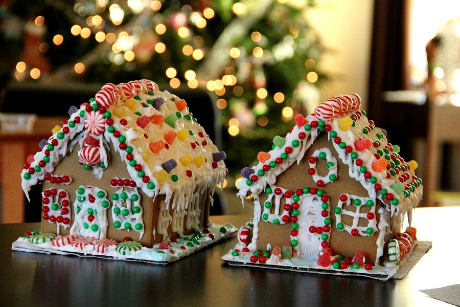 Things to Do on Christmas Morning Close Up of Two Gingerbread Houses with a Christmas Tree in the Background