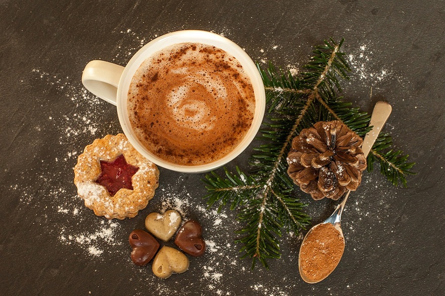 Things to Do on Christmas Morning Overhead View of a Mug Filled with Hot Chocolate Next to a Cookie, a Pine Cone and Some Pine Needles