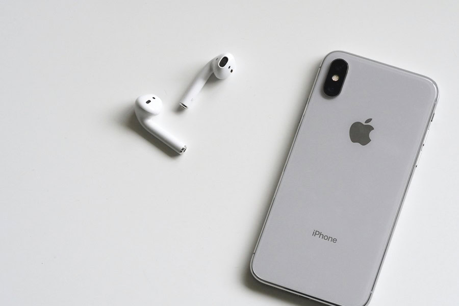 15 iPhone Wallpapers to Inspire Anyone Close Up of an iPhone Next to Air Buds on a White Surface