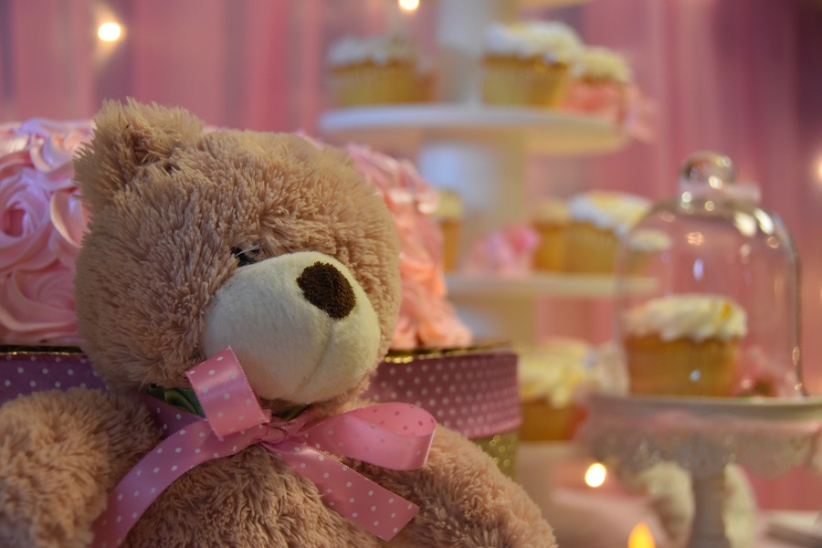 Baby Shower Cakes for Girls Close Up of a Teddy Bear with Pink Decor and Cupcakes in the Background