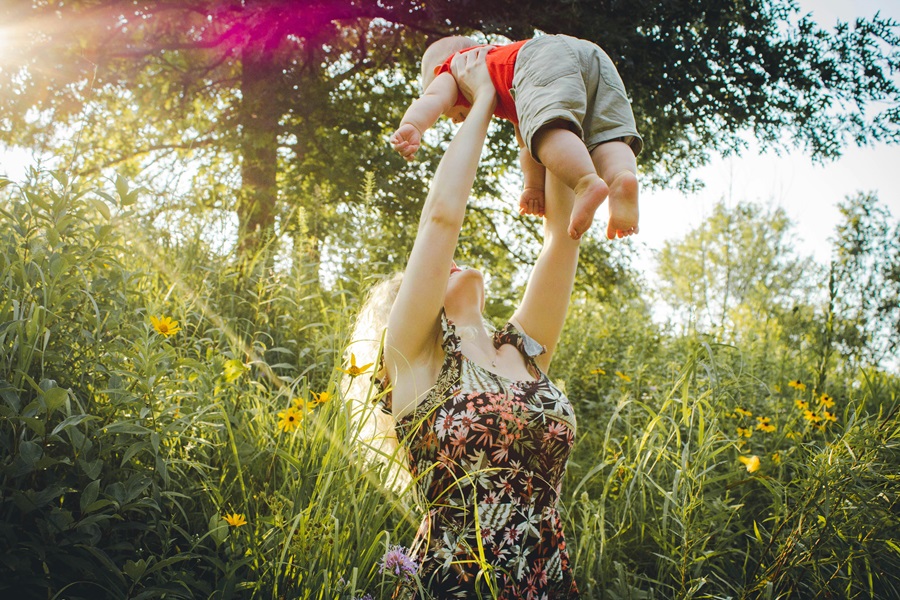 Mother's Day Quotes a mom in a park Holding Her Baby Up in the Air for Fun
