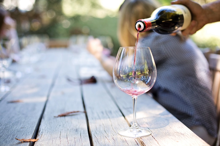 DIY Boozy Gifts for Wine Lovers Close Up of a Person Pouring Wine into a Wine Glass on a Picnic Table Outside
