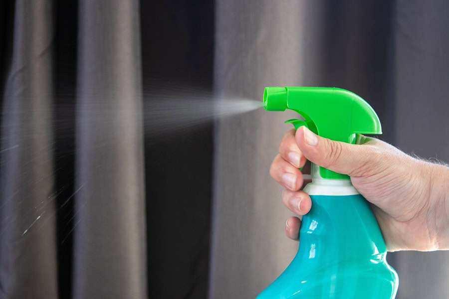 Hydrogen Peroxide Cleaner DIY Recipes Close Up of a Green Spray Bottle Being Squeezed by a Person's Hand