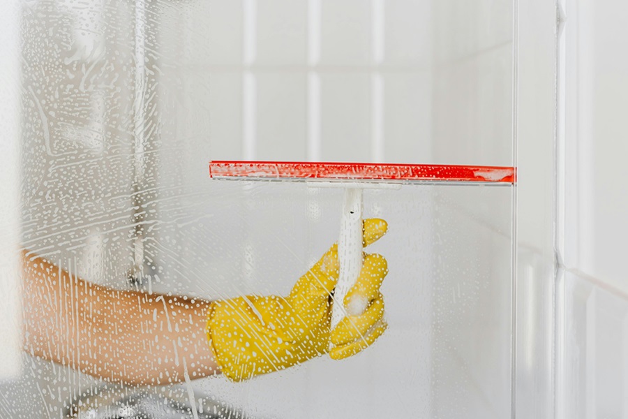 Hydrogen Peroxide Cleaner DIY Recipes Close Up of a Squeegee Wiping Cleaner Off a Glass Shower Door 