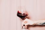 Drinking Games for Two {Wine, Beer, and More} Close Up of a Hand Holding a Glass of Red Wine in Front of a Pink Wall