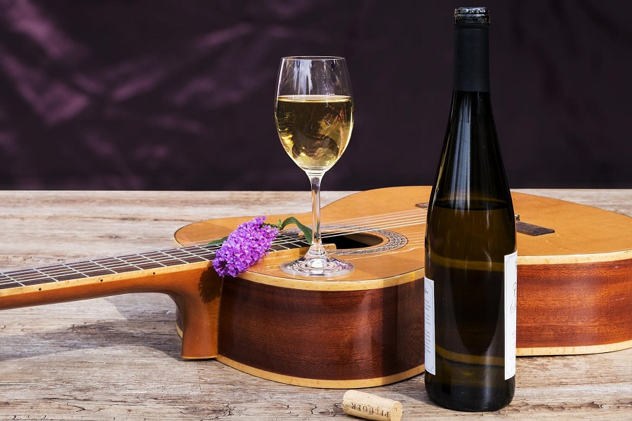 White Wines Under 10 Dollars A Guitar Laying on a Surface with a Glass of White Wine Sitting On Top of it and a Bottle of Wine Sitting Next to it