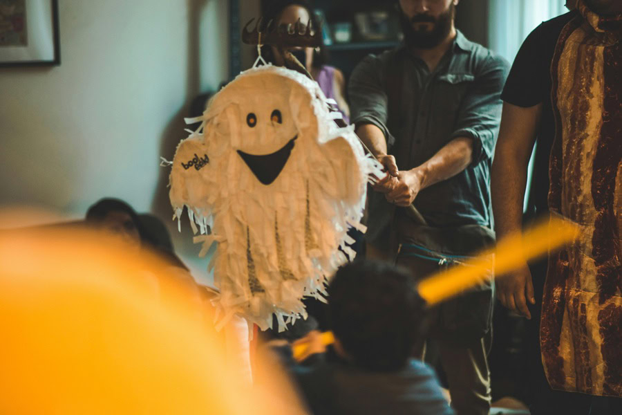 Halloween Party Recipes a Group of People Hitting a Ghost-Shaped Pinata at a Party