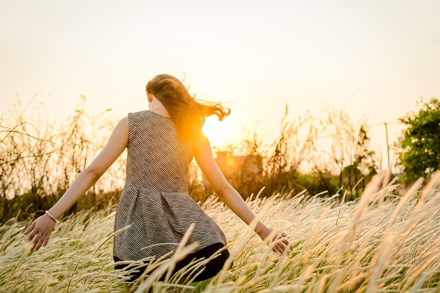 Courage Quotes for Women a Woman in a Dress Walking Through a Field of Tall Grass With Her Arms Stretched Out