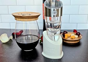 Stainless Steel Luxury Adjustable Wine Aerator On a Counter with a Half Filled Wine Glass and Wine Topper Next to it