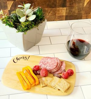 Angled View of a Personalized Mini Charcuterie Board with Meat and Fruit and a Wine Glass Filled with Red Wine