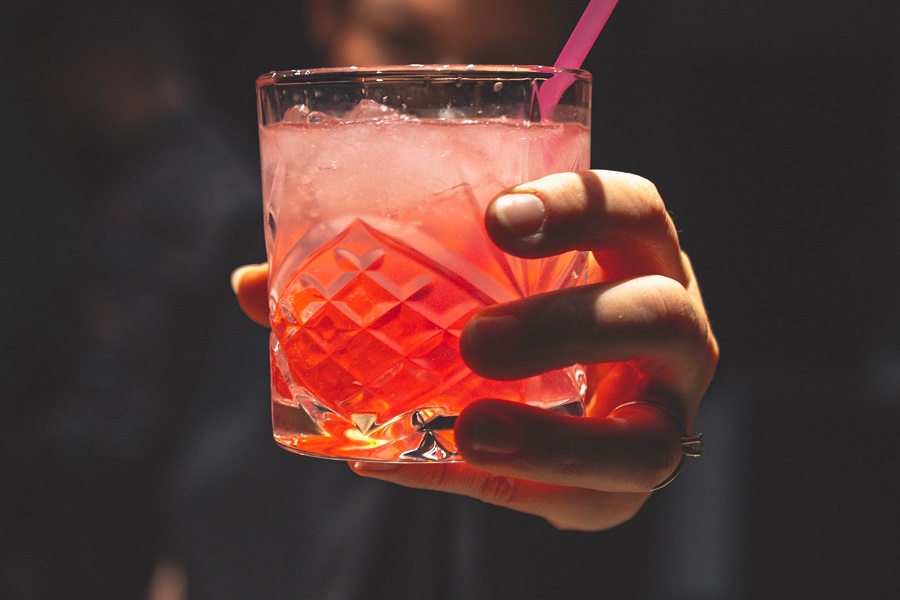 Tequila Drinks that Aren't Margaritas Close Up of a Bartender's Hand Holding Out a Pink Cocktail