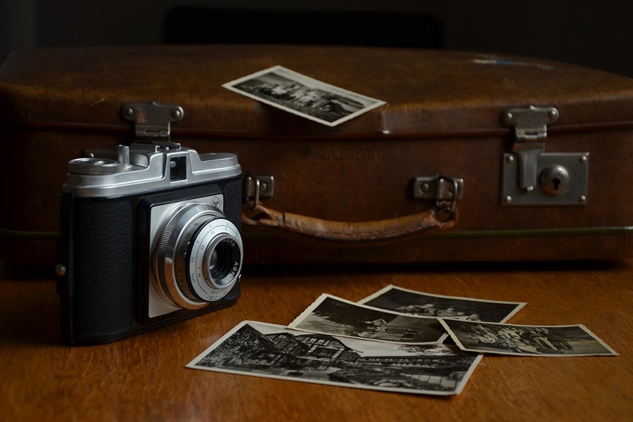 Photography Poses to Up your Photo Game a Vintage Camera Sitting on a Wooden Surface Next to a Suitcase with Pictures Scattered Around