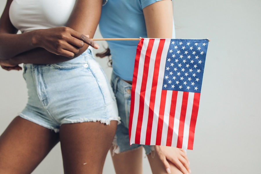 Fourth of July Facts to Know Two People Standing Next to Each Other Holding an AmericanFlag