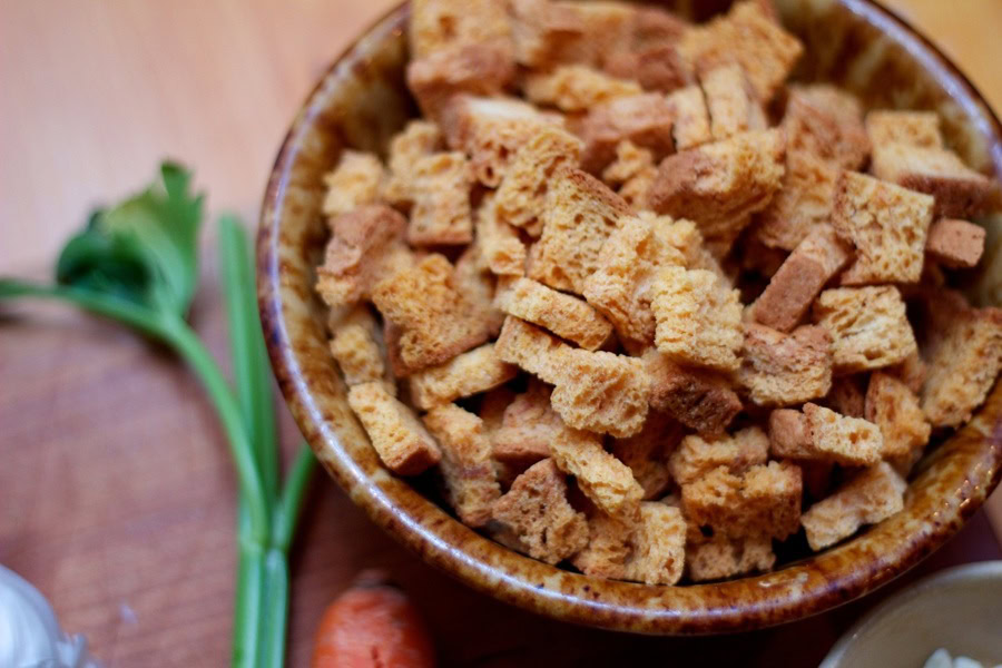 Best Thanksgiving Stuffing Recipes Overhead View of a Bowl of Bread Chunks with Celery Next to it