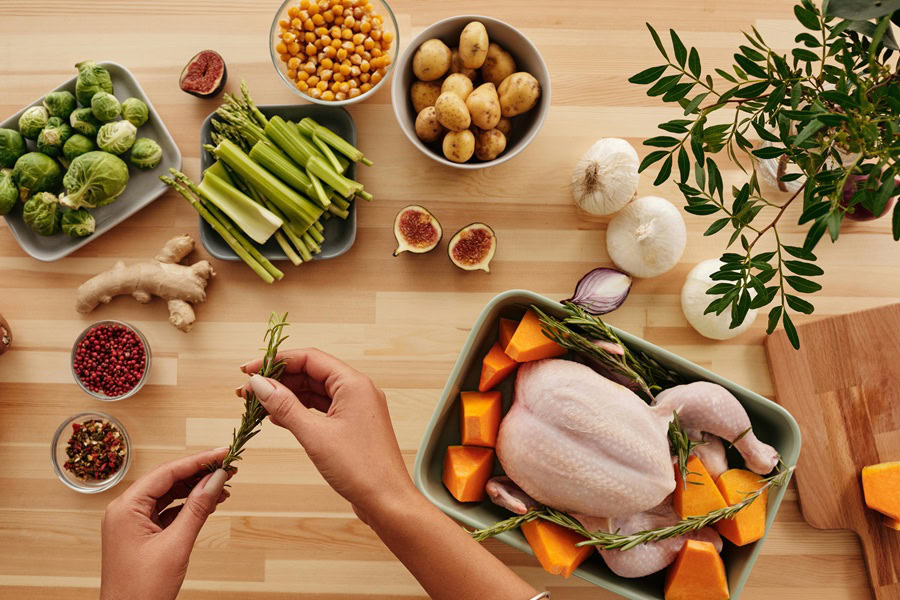 Best Thanksgiving Stuffing Recipes View of Someone Preparing a Turkey to Bake with Veggies and Herbs All Around