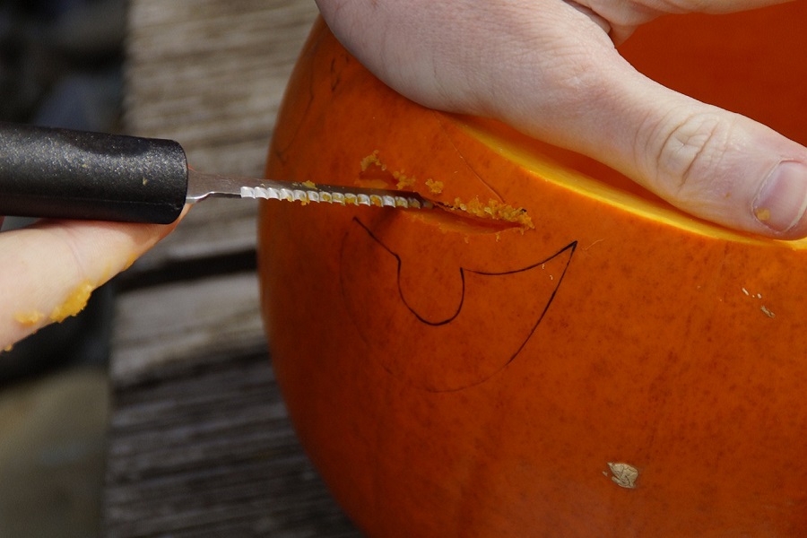 DIY Pumpkin Decorating Ideas Close Up of a Person Carving a Pumpkin