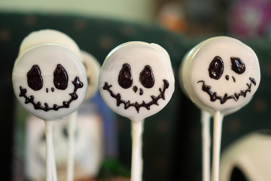 Halloween Party Food Ideas for Kids Close Up of Oreos Dipped in White Chocolate on Sticks with Jack Skellington Faces Painted On Them