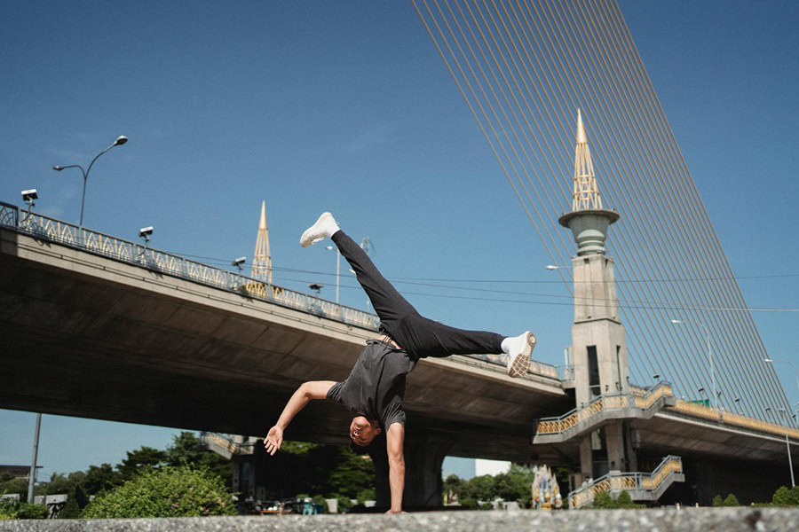 Muffin Top Workouts a Man Breakdancing in Front of a Bridge