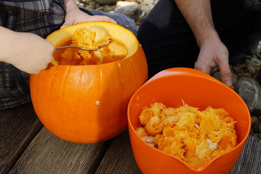 Pumpkin Carving Ideas View of a Pumpkin Being Carved and a Bowl Filled with Pumpkin Guts Next to it
