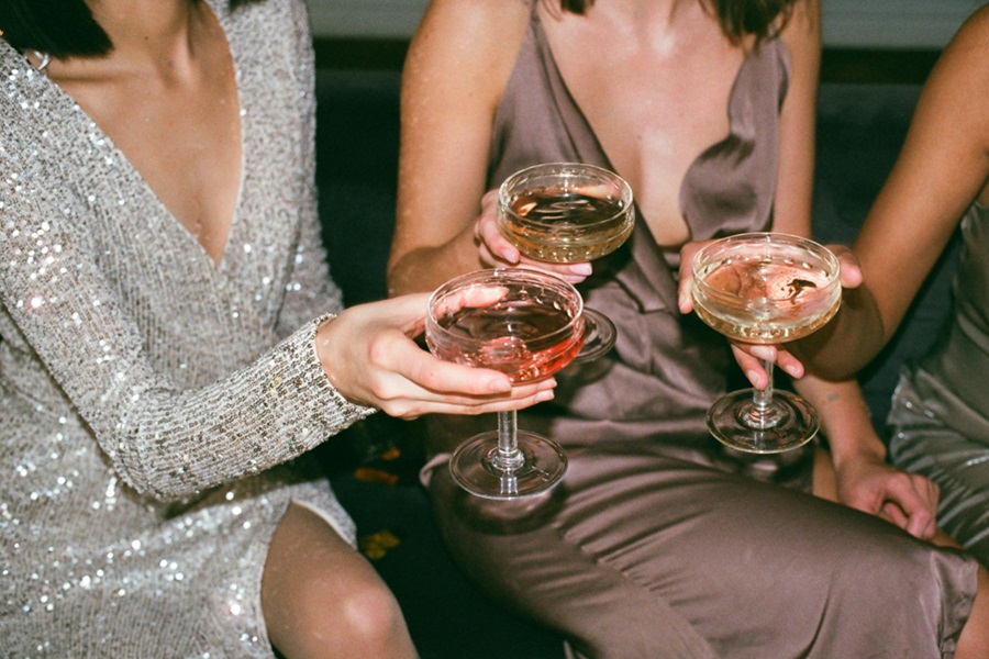 11 Funny Bachelorette Party Ideas and Games Close Up of Women Sitting Together Holding Glasses of Champagne