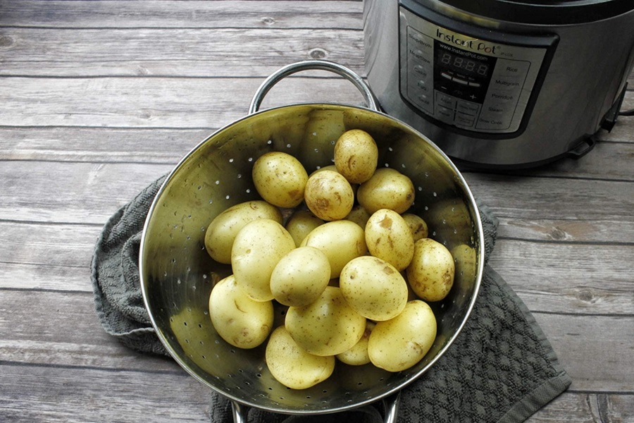 How to Use an Instant Pot Close Up of a Strainer Filled with Peeled and Rinsed Potatoes Next to an Instant Pot