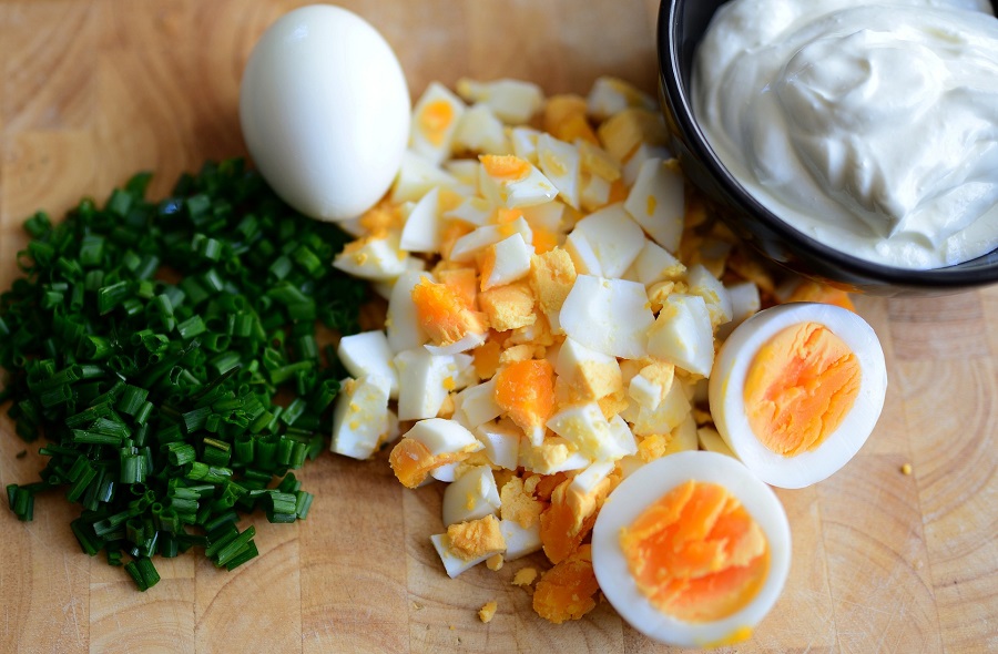 Make Ahead Whole30 Breakfast Recipes Overhead View of Hard Boiled Eggs Next to Chopped Chives and a Small Bowl of Cream