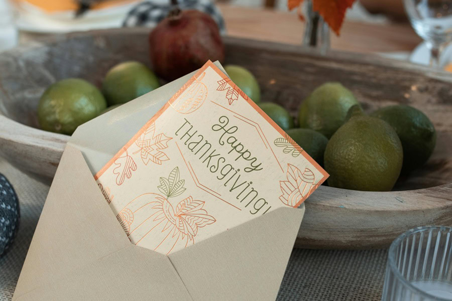 Printable Thanksgiving Games a Happy Thanksgiving Card Sticking Out from an Envelope Leaning Against a Small Fruit Dish with Apples on a Table