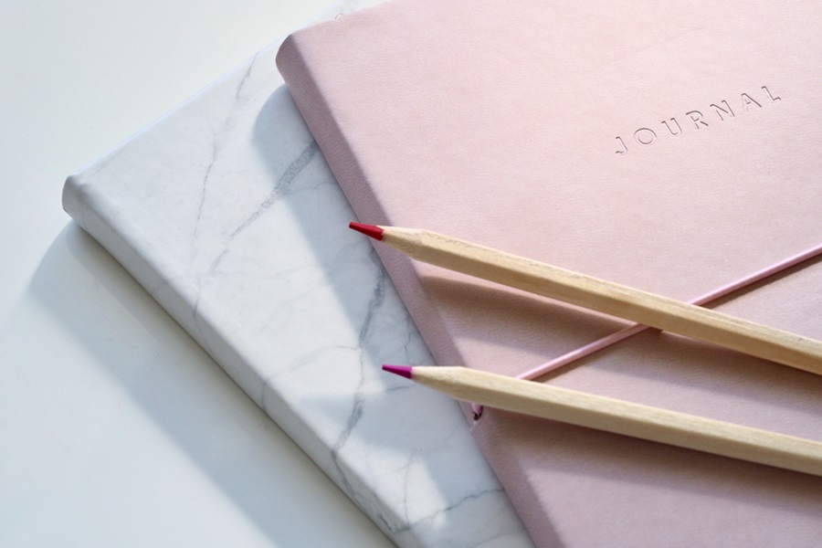 How to Set up your Bullet Journal for the New Year Close Up of a Pink Bullet Journal On Marble with Two Pink Pencils On Top