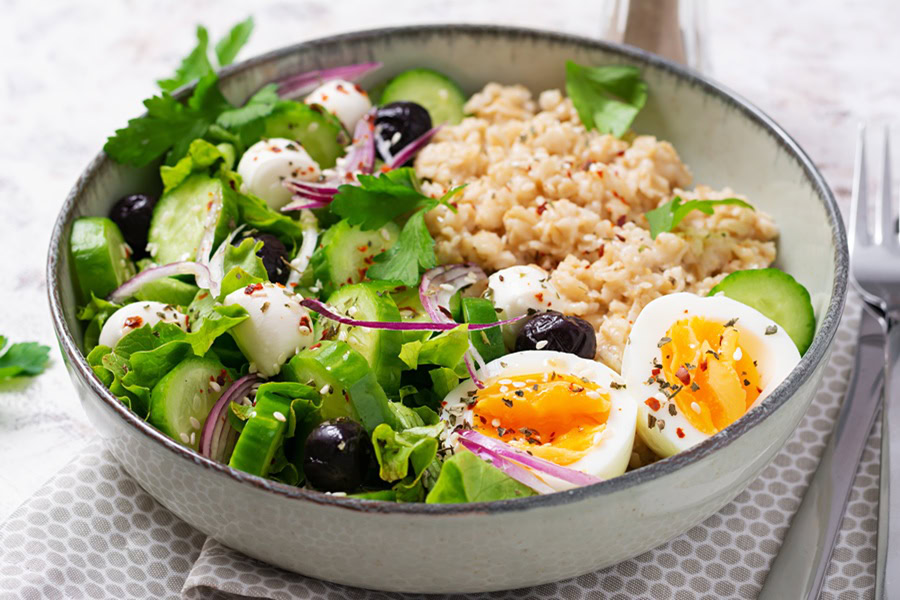 Savory Oatmeal Recipes Breakfast oatmeal porridge with boiled eggs, cucumber, mozzarella cheese and green herbs. Healthy balanced food.