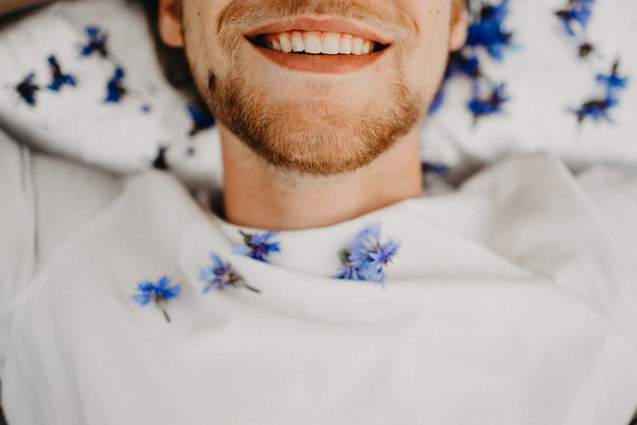 Quotes About New Beginnings Close Up of a Man Lying Down, Smiling, Surrounded by Blue Flowers