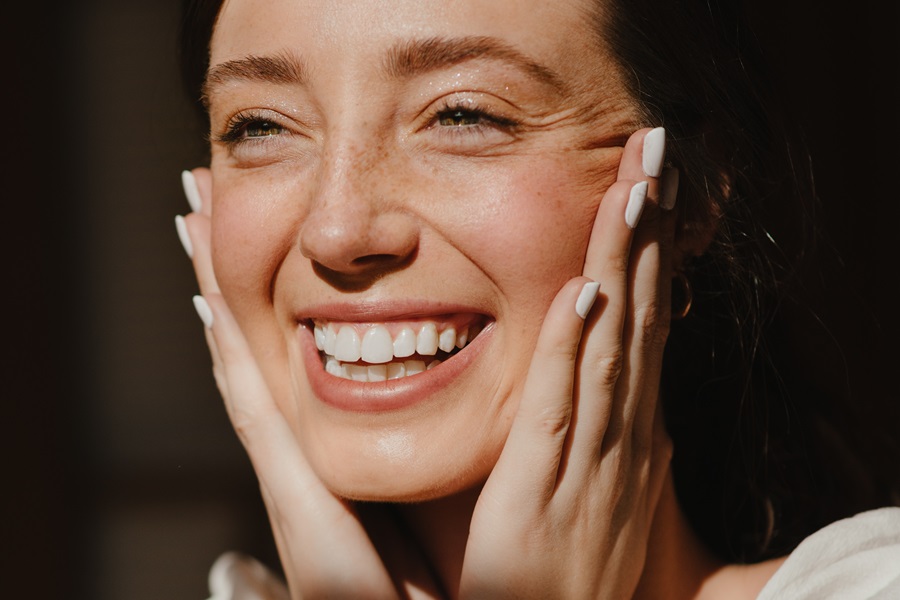 Quotes About New Beginnings Close Up of a Woman Smiling Holding Her Own Face with Her Hands