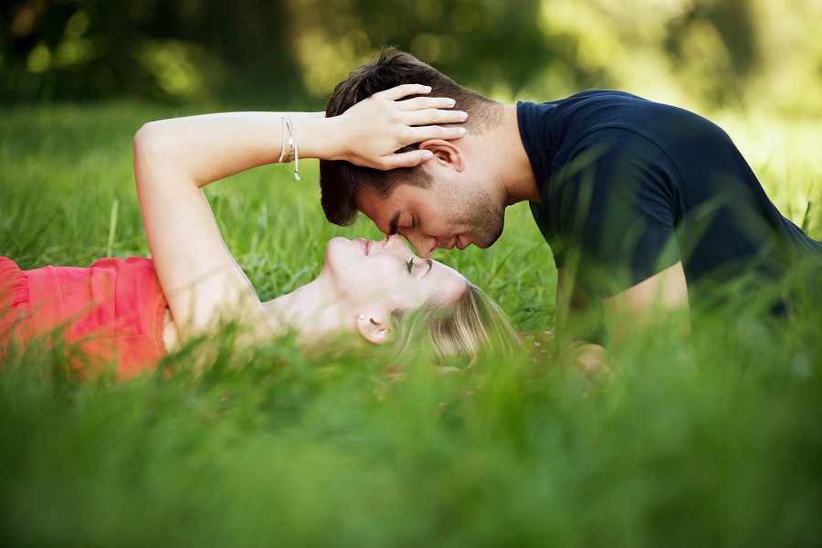 Romantic Valentine's Day Quotes for Him Woman Laying Down on the Grass Holding a Man's Head as he Leans Over Her Kissing Her Forehead
