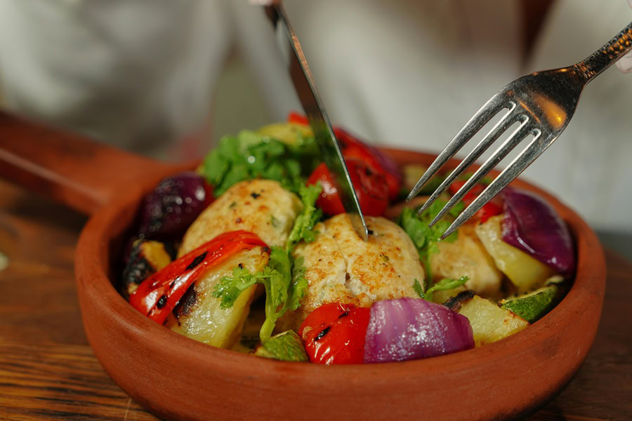 Whole30 Instant Pot Chicken Recipes Close Up of a Plate of Chicken with Veggies and a Person Holding a Fork and a Knife To The Chicken on the Plate