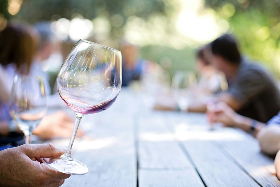 Wine Tasting Tips you Need to Know Close Up of a Person's Wine Glass as They Hold it Over a Picnic Table