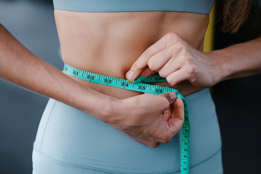 Best Ways to Lose Water Weight a Women Tightening a Measuring Tape Around Her Waist